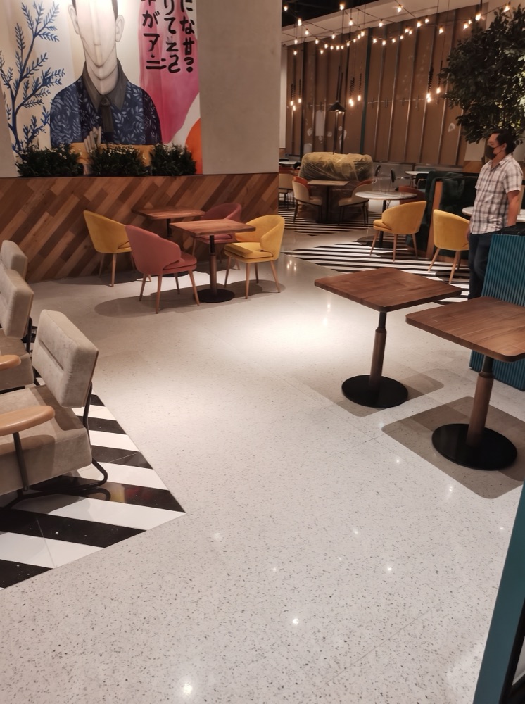 White terrazzo dining floor with black-and-white tile borders at Falla, Mirdif Mall, Dubai — supplied by Mina Surface