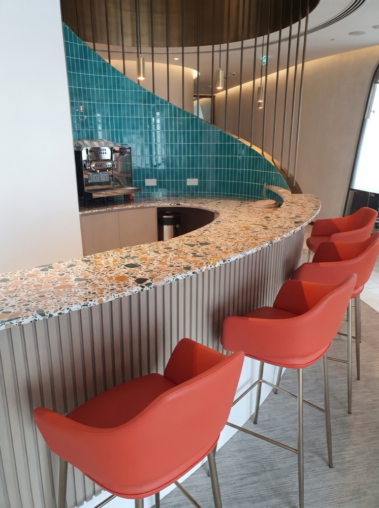 Curved coffee-bar counter in multicolour aggregate terrazzo at the Malvyn corporate office, Dubai — supplied by Mina Surface